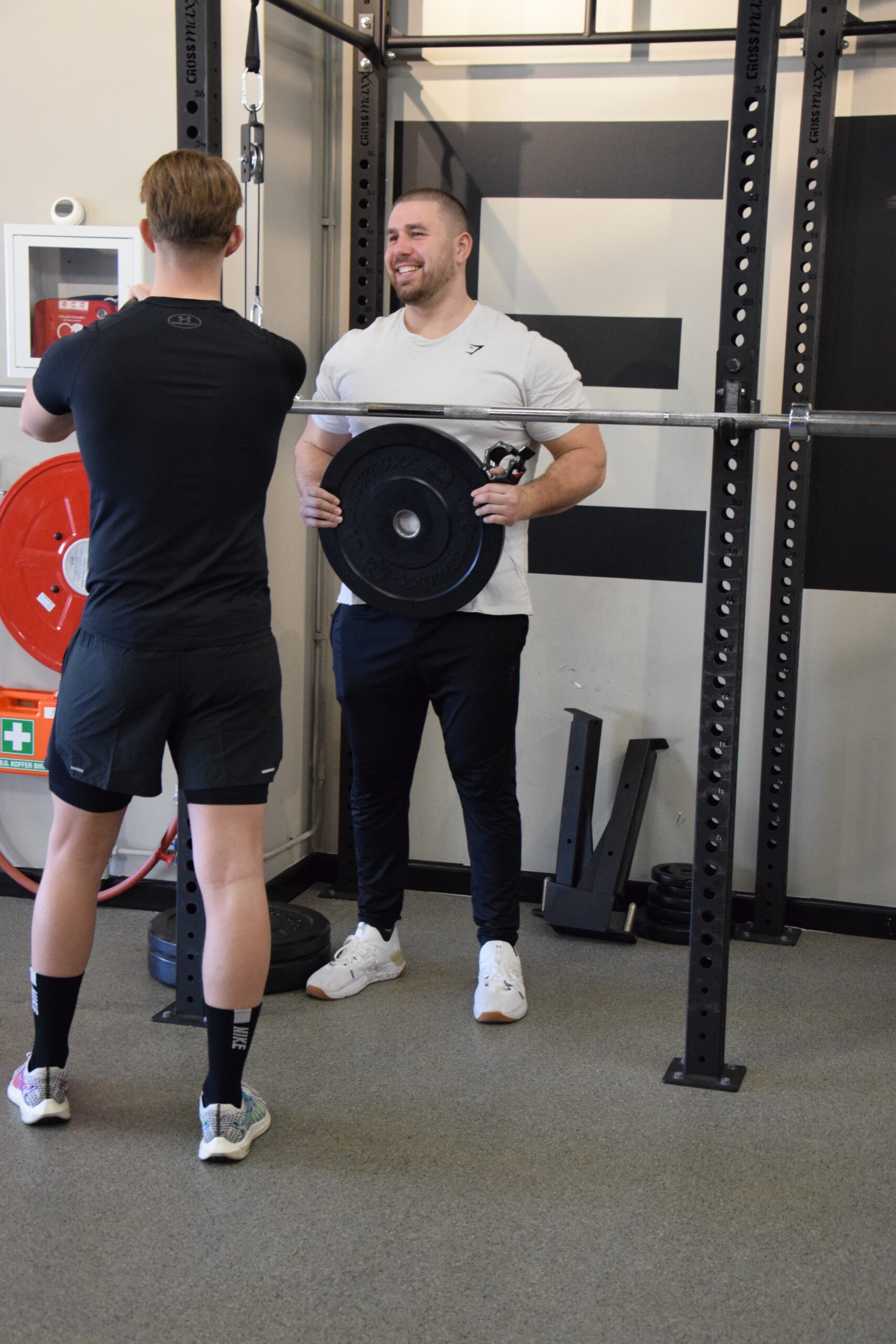 Personal trainer carries a weight to put on a barbell/bar for his client.