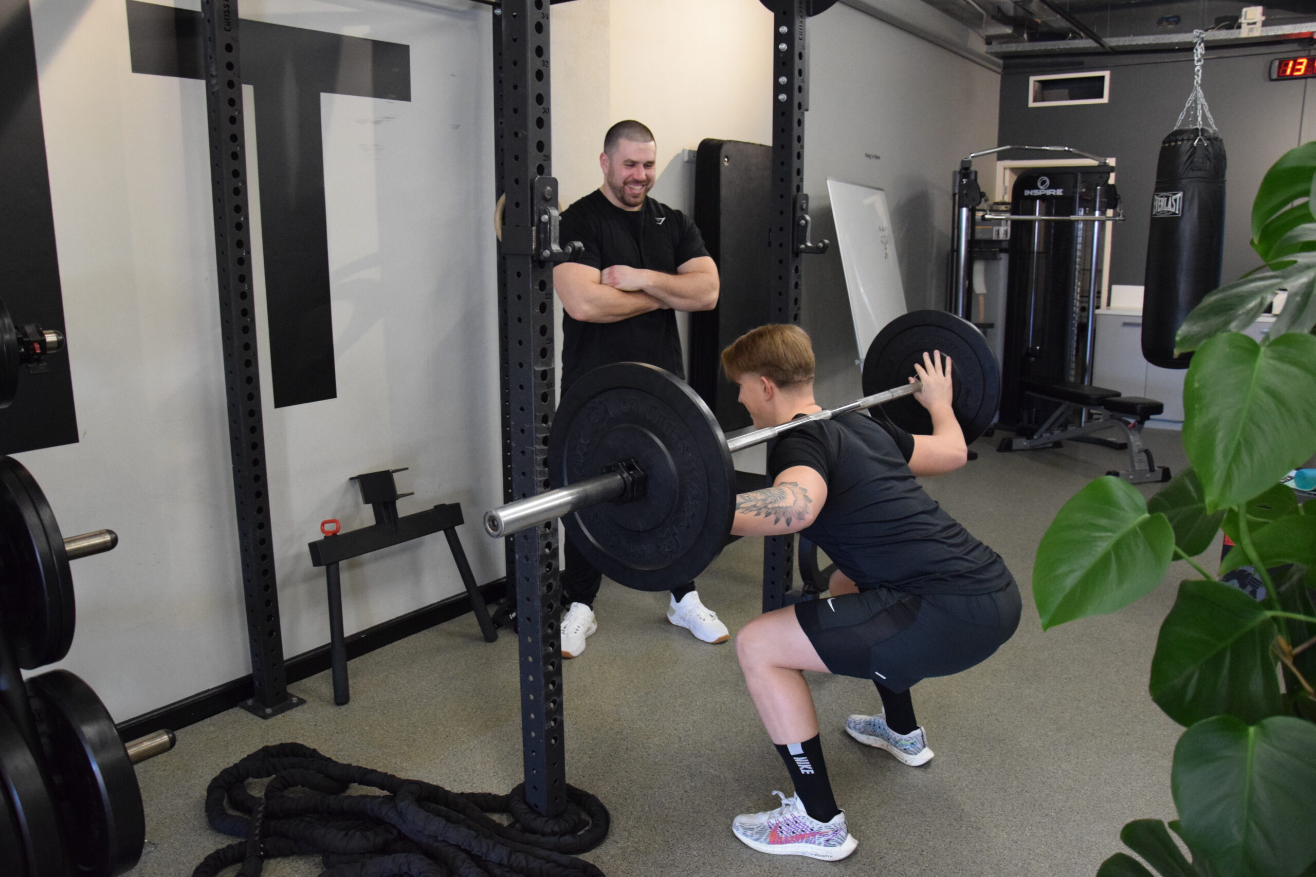 A coach/Personal trainer giving cues to a client while performing a squat.