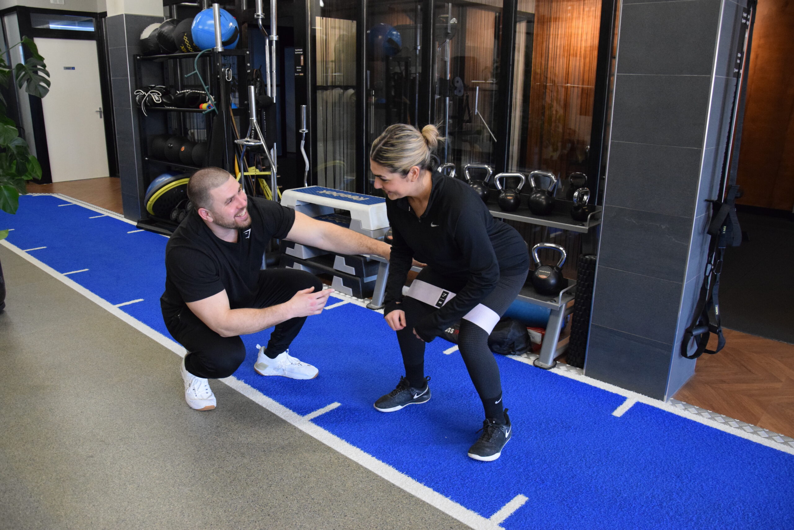 Coach/trainer giving cues to a client that is performing a banded exercise.